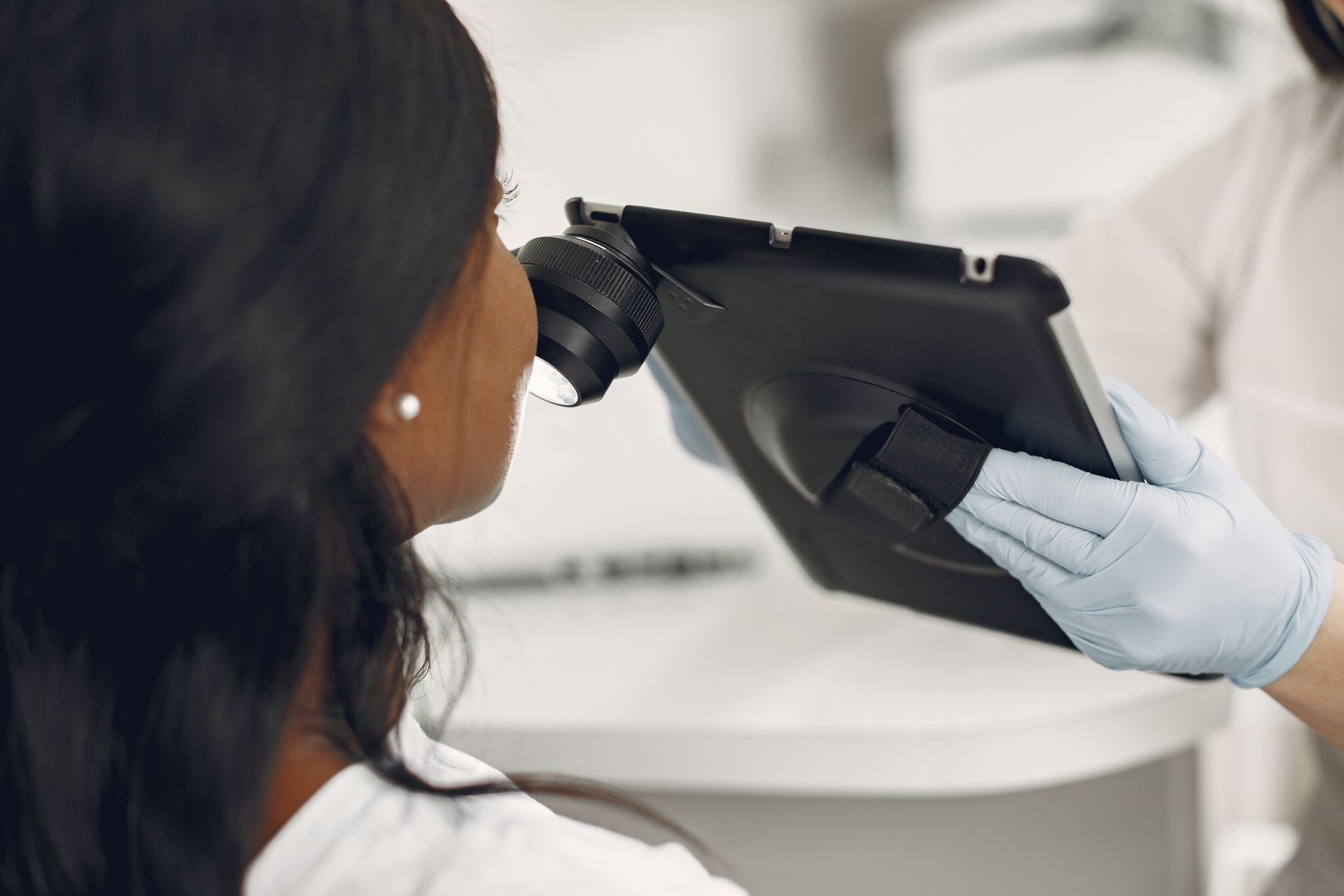A dermatologist examining a patient's skin with a digital dermatoscope