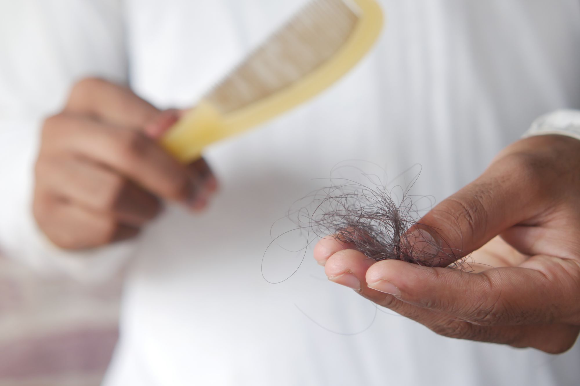 Loose hair gathered in a hand next to a comb
