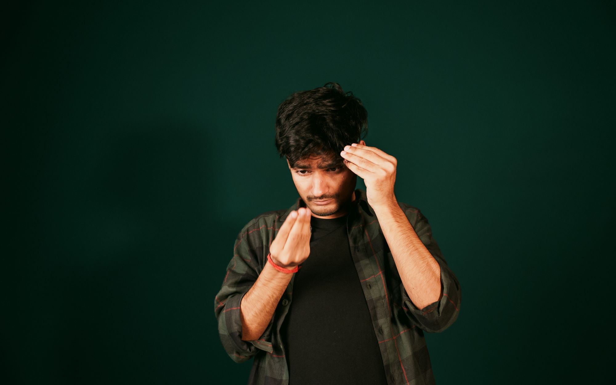A man checking his hairline against a dark green background