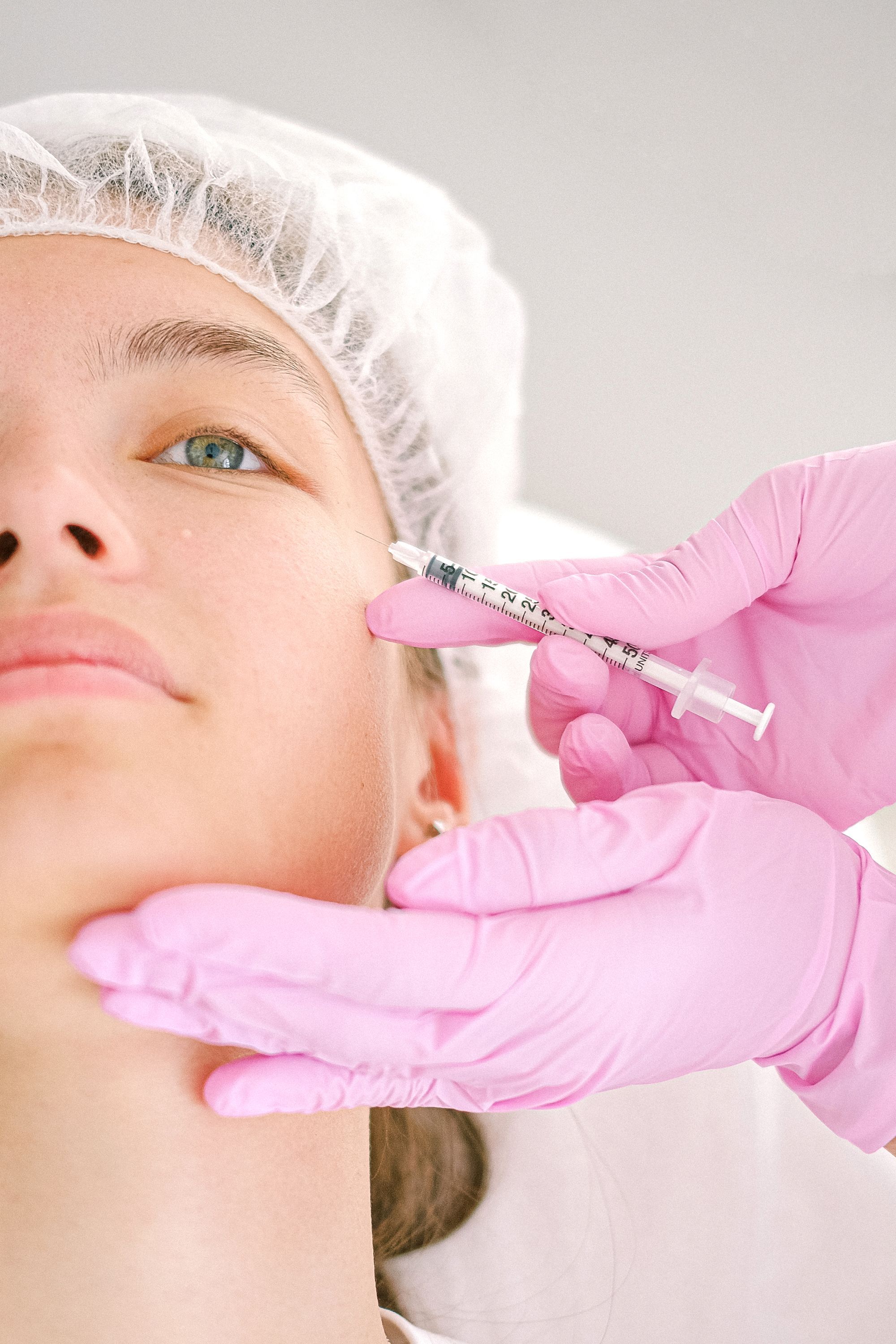 A gloved injector treating the side of a patient's face