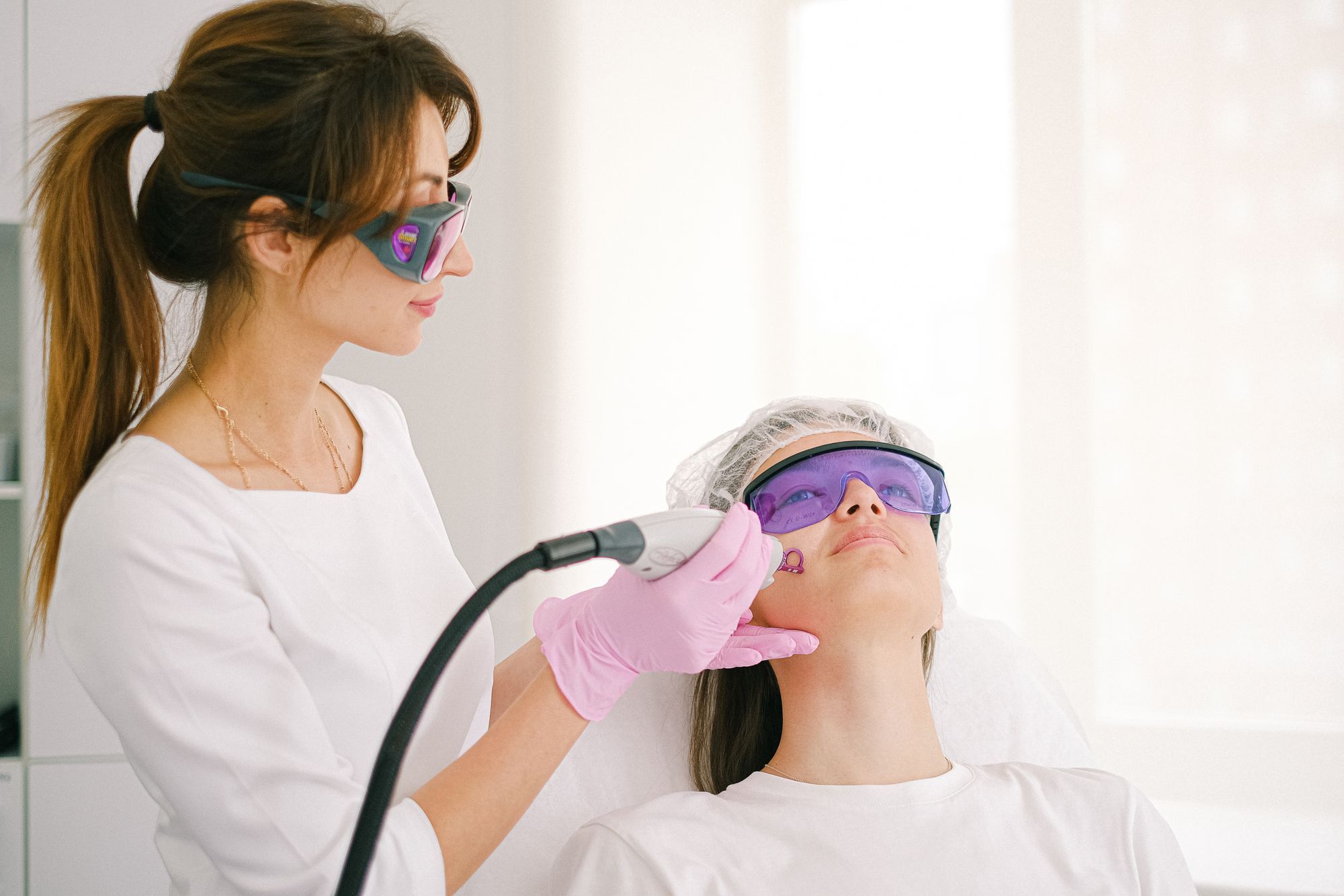 A clinician treating a patient in protective glasses with a handheld laser