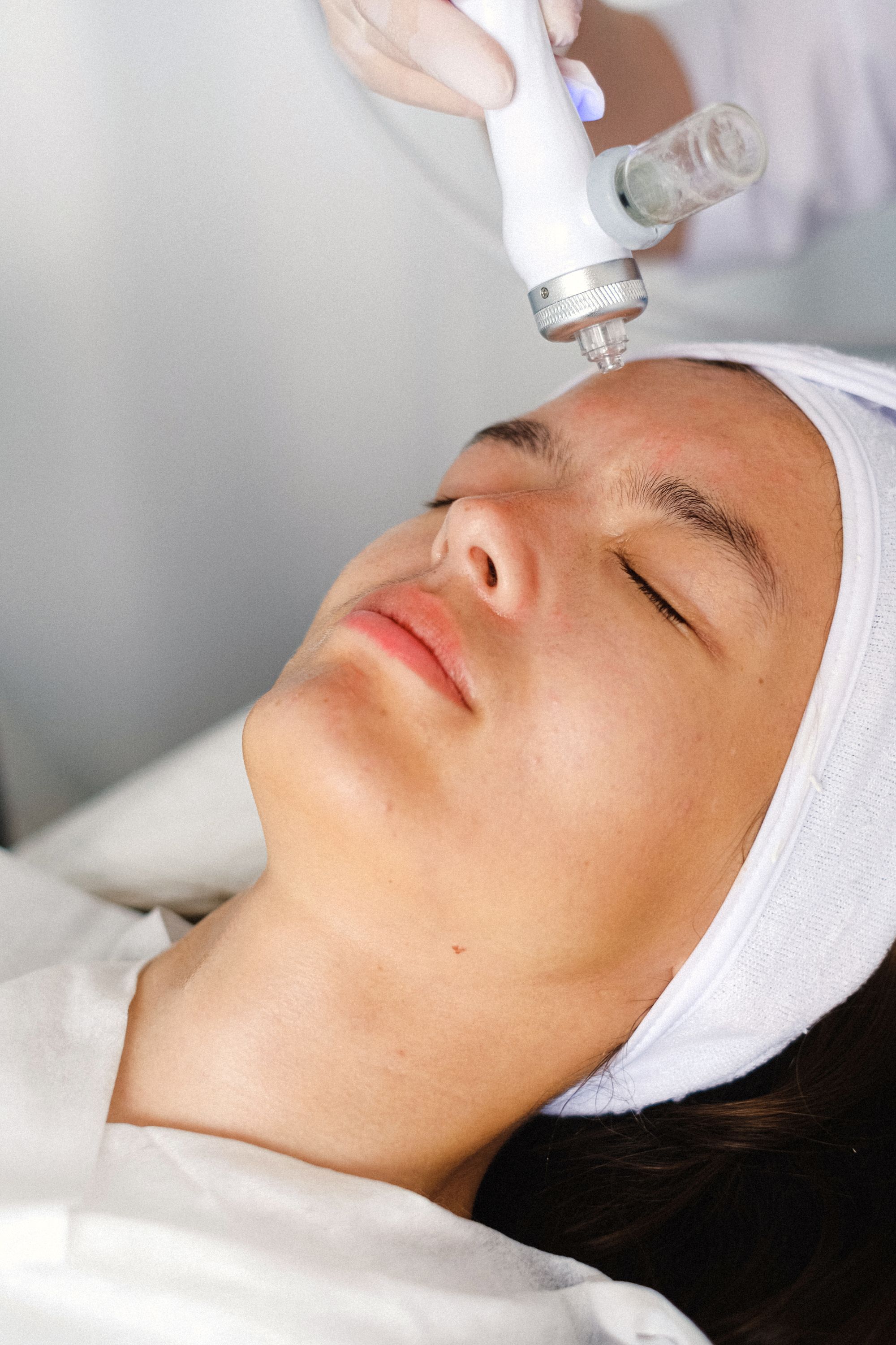 A gloved hand guiding a laser tool across a patient's face