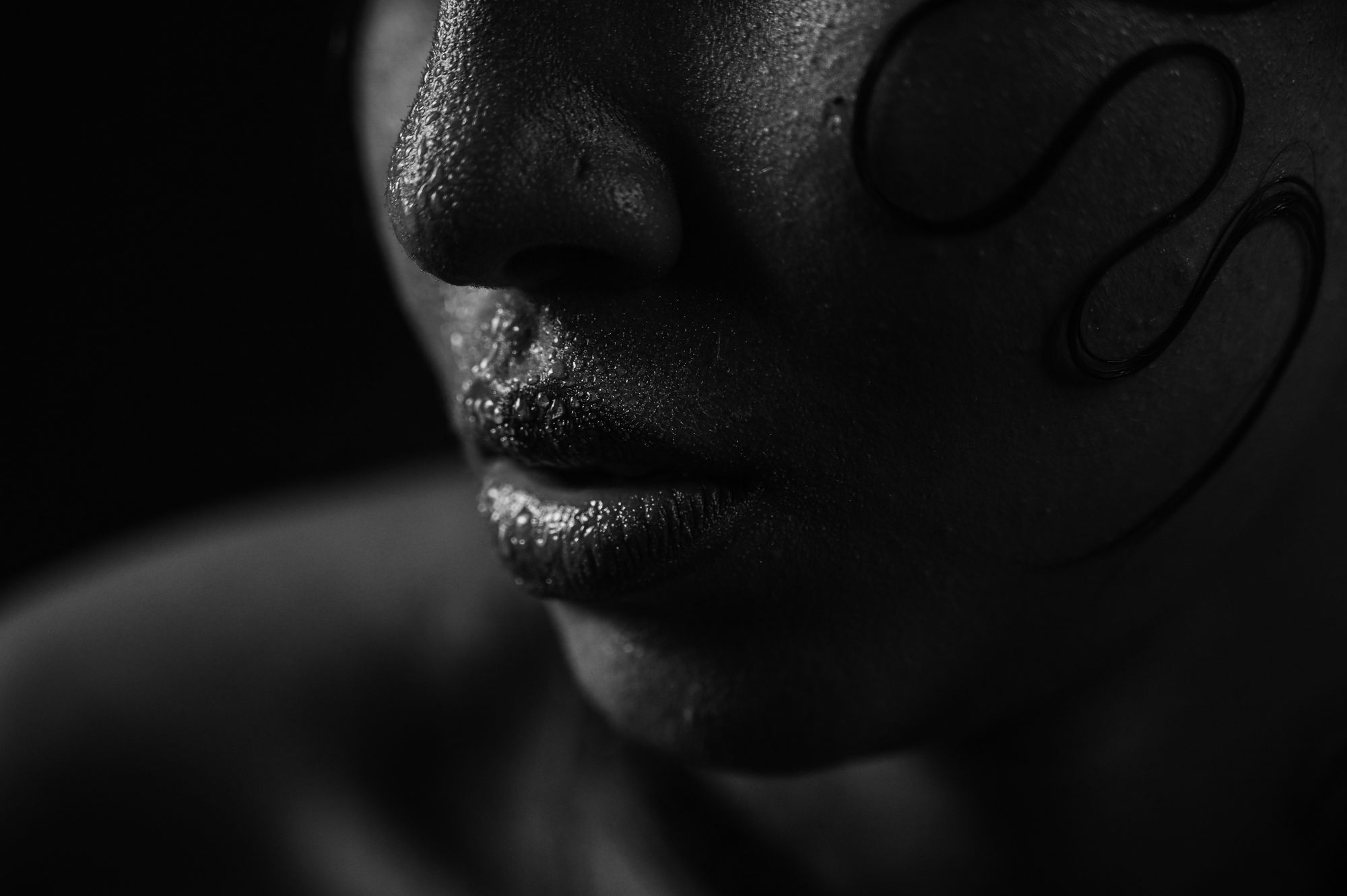 Black and white close-up of a face, lips and cheek in hard light